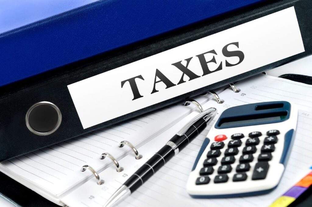 Binder labeled taxes with calculator and notebook, symbolizing OBBB tax provisions and deductions for Texas real estate investors.