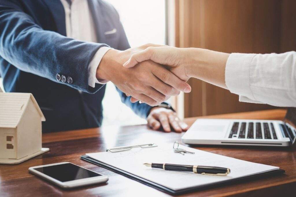 Real estate investors shaking hands over property investment agreement, symbolizing how to adapt portfolios under OBBB in Texas.