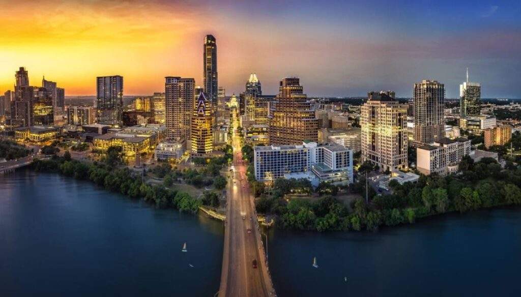 Austin, Texas Skyline at Sunset: Panoramic view of the downtown towers and the bridge over the Colorado River, symbolizing Texas market growth and domestic resilience.