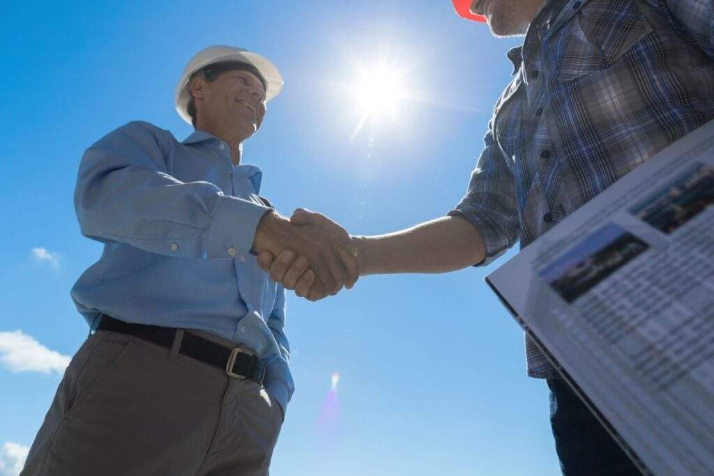 Builder Handshake: Architect and contractor securing partnership and fixed-rate contracts on a construction site.