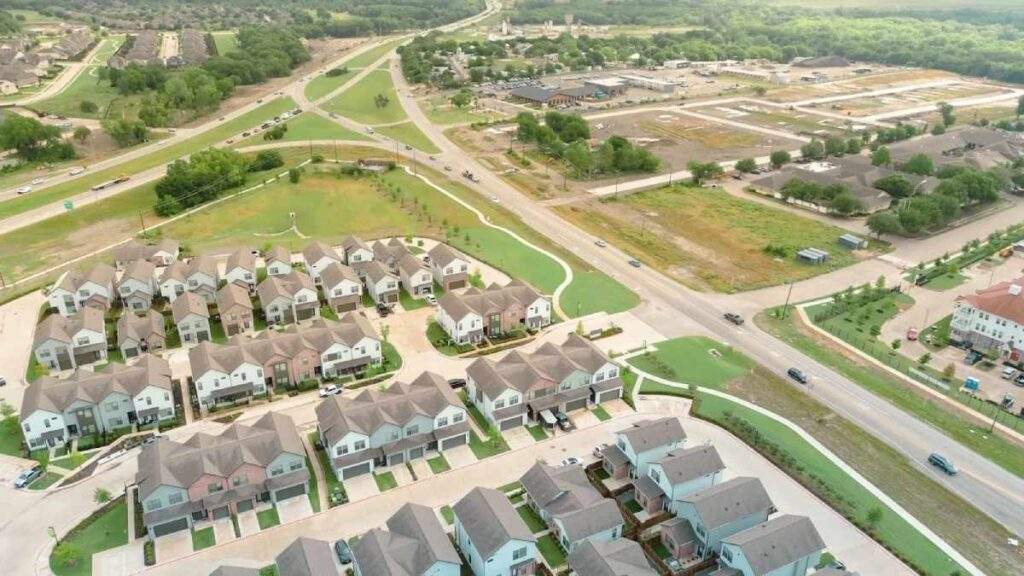 Aerial view of a new Texas suburban townhouse development near a major highway exit.