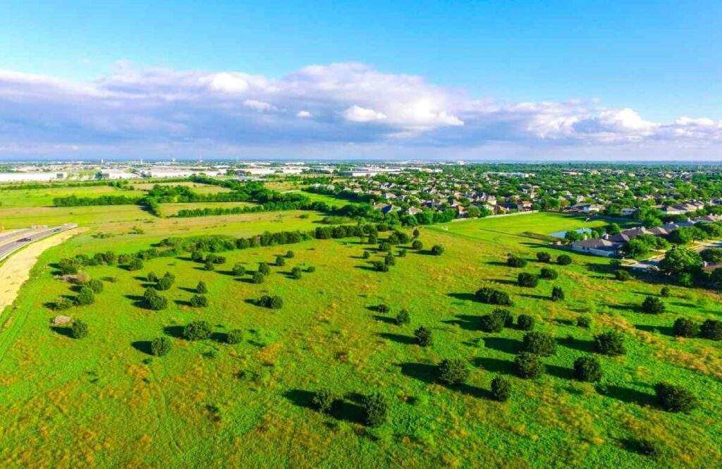 Aerial view of undeveloped land near residential communities in Texas suitable for real estate investment or donation.