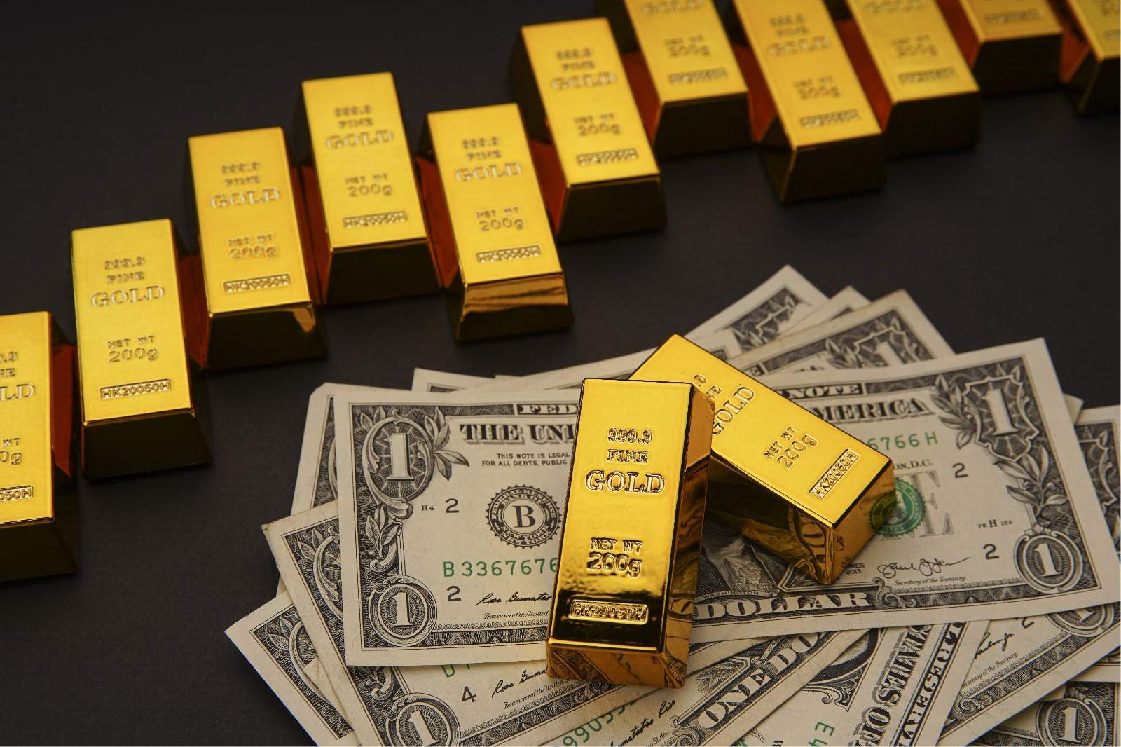Stacked gold bars beside US dollar banknotes representing central bank reserves and hard asset investment strategy